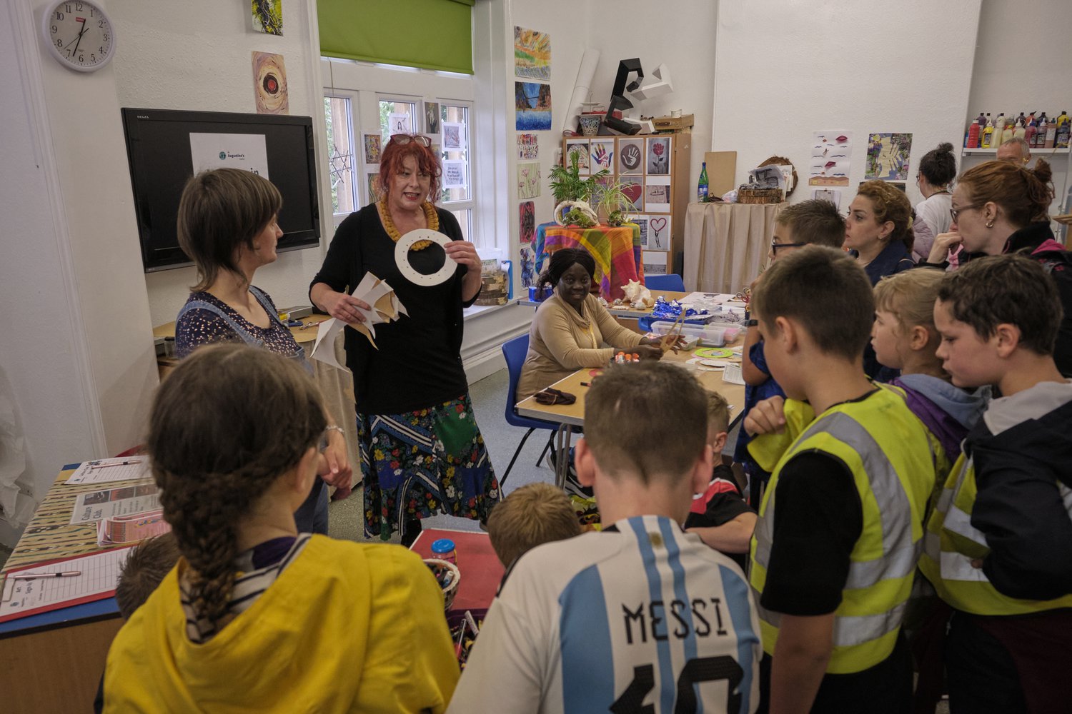 Woman holding artwork to a group of school children and talking about it