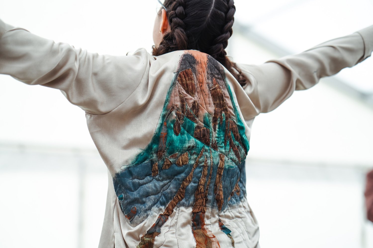 image of the back of a woman spreading her arms and a volcano on her shirt